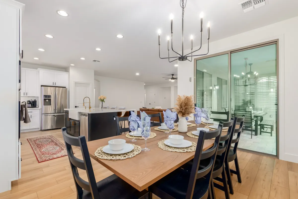 A warmly set dining table beneath a charming chandelier, adjacent to a kitchen island and decorated for a special meal. The atmosphere encourages both festive gatherings and intimate family dinners.